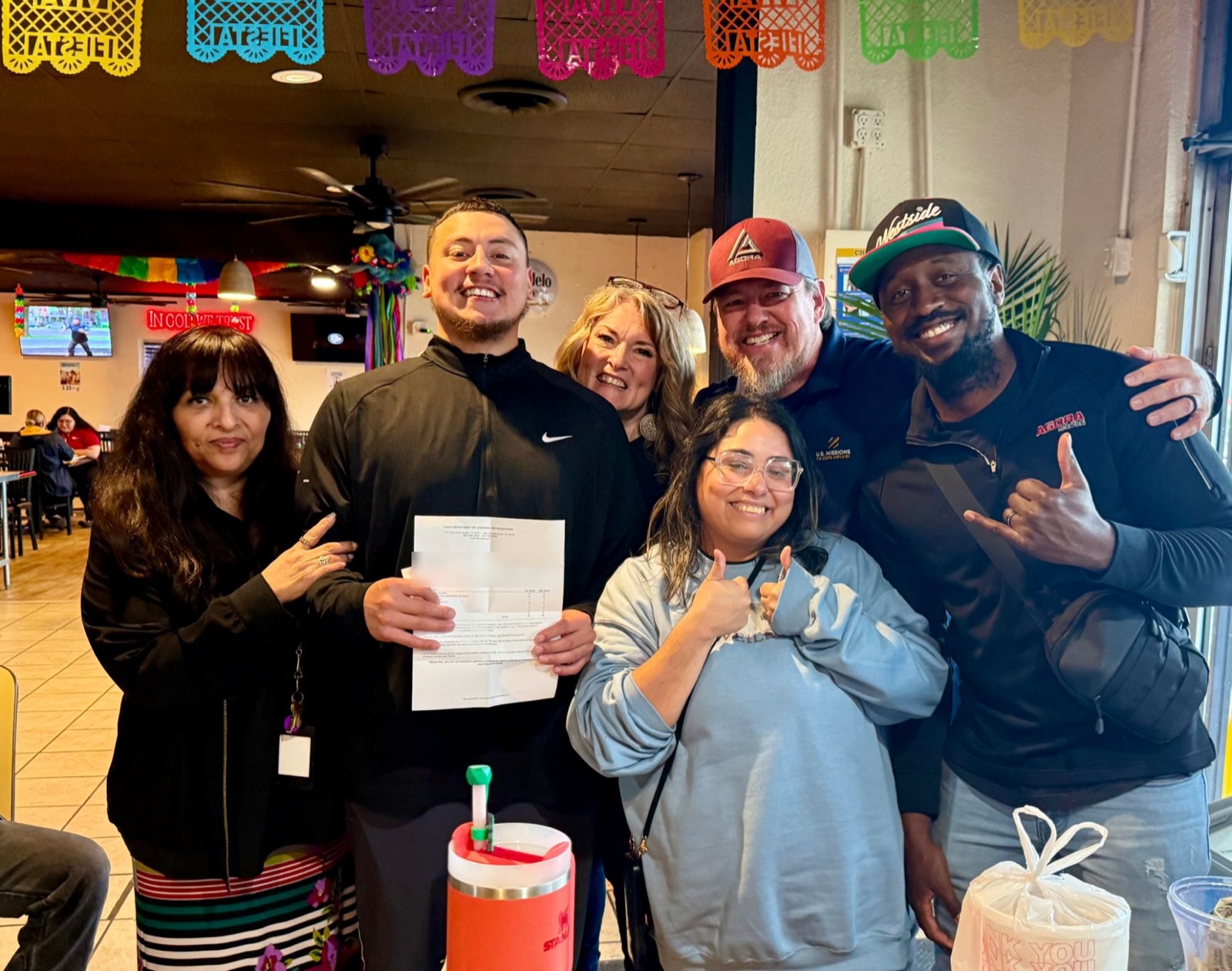 AGORA staff celebrating with a student who passed his Texas barber licensing exam