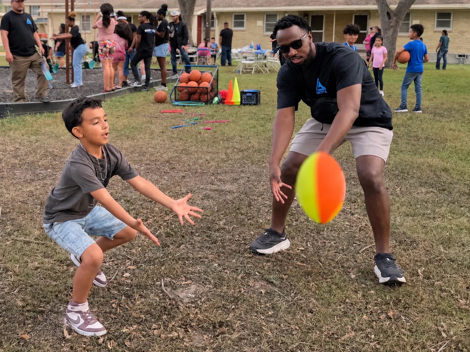 An AGORA mentor tossing a ball with a boy at a neighborhood sports outreach